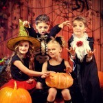 Cheerful children in halloween costumes celebrating halloween in a wooden barn with pumpkins. Halloween concept.