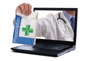 Internet drug store concept doctor holding prescription medicine through a laptop screen